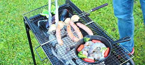 芝生の上で新鮮な野菜と肉を焼いている人